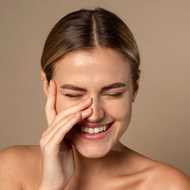 Chica joven sonriente posándose la mano e el rostro