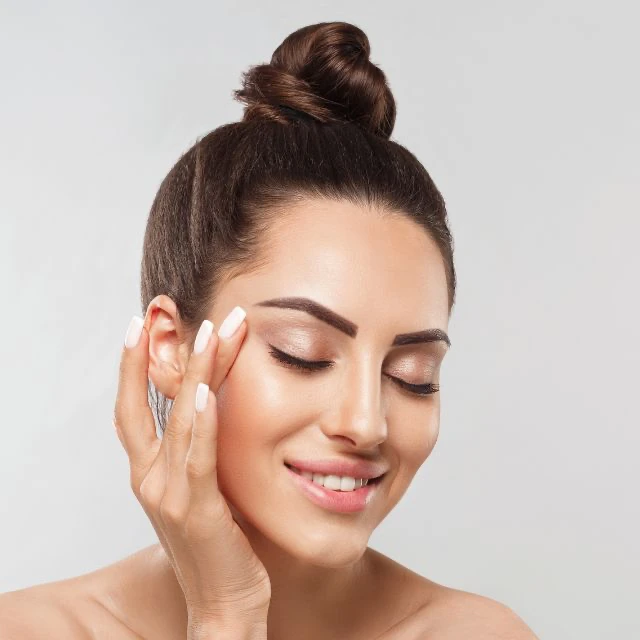 Chica sonriente tocándose ligeramente el rostro